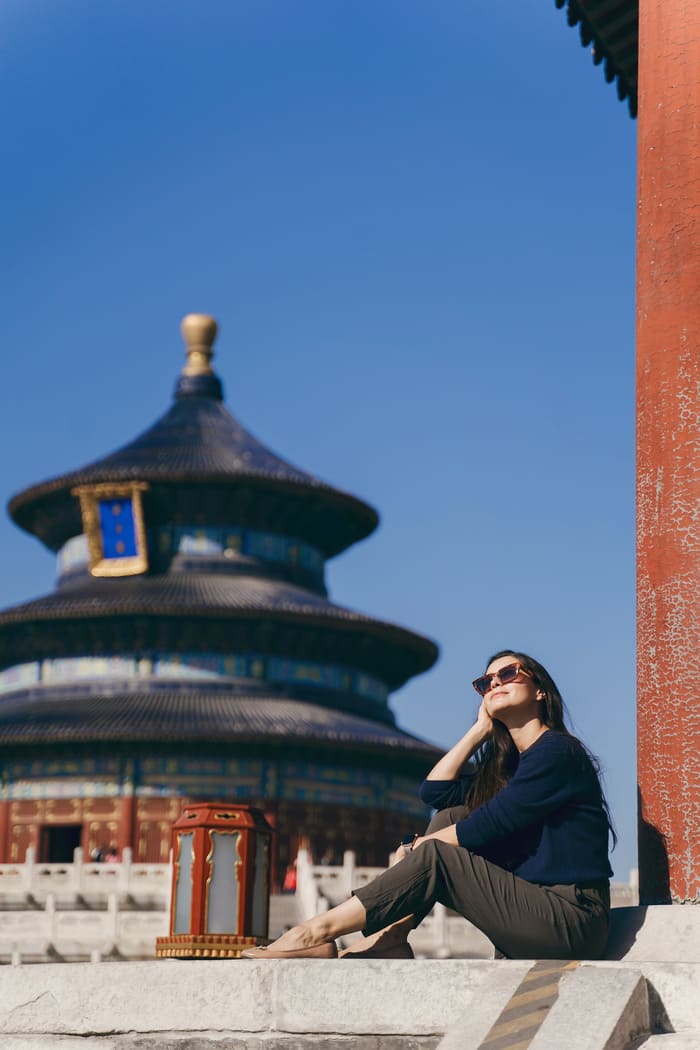 Mujer sentada posando frente a un templo chino de Beijing.