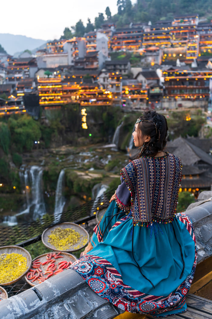 Mujer sentada viendo un paisaje de la ciudad de Lijiang