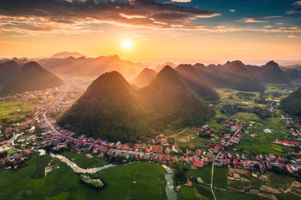 Montañas de Yangshuo en el amanecer con la ciudad rodeandolas, entre un paisaje verde.